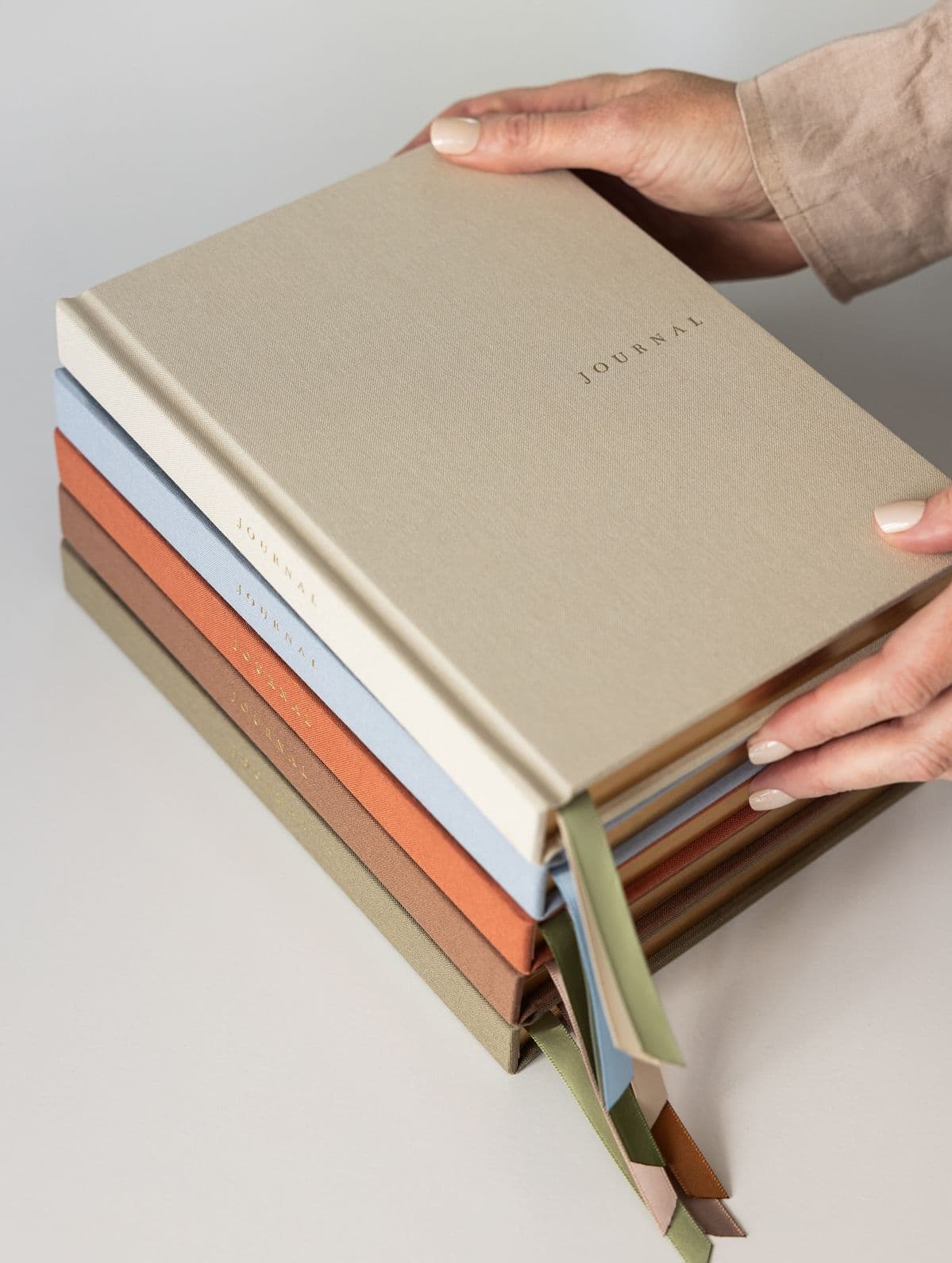 Journals de tela con listón en arena, azul, naranja y café